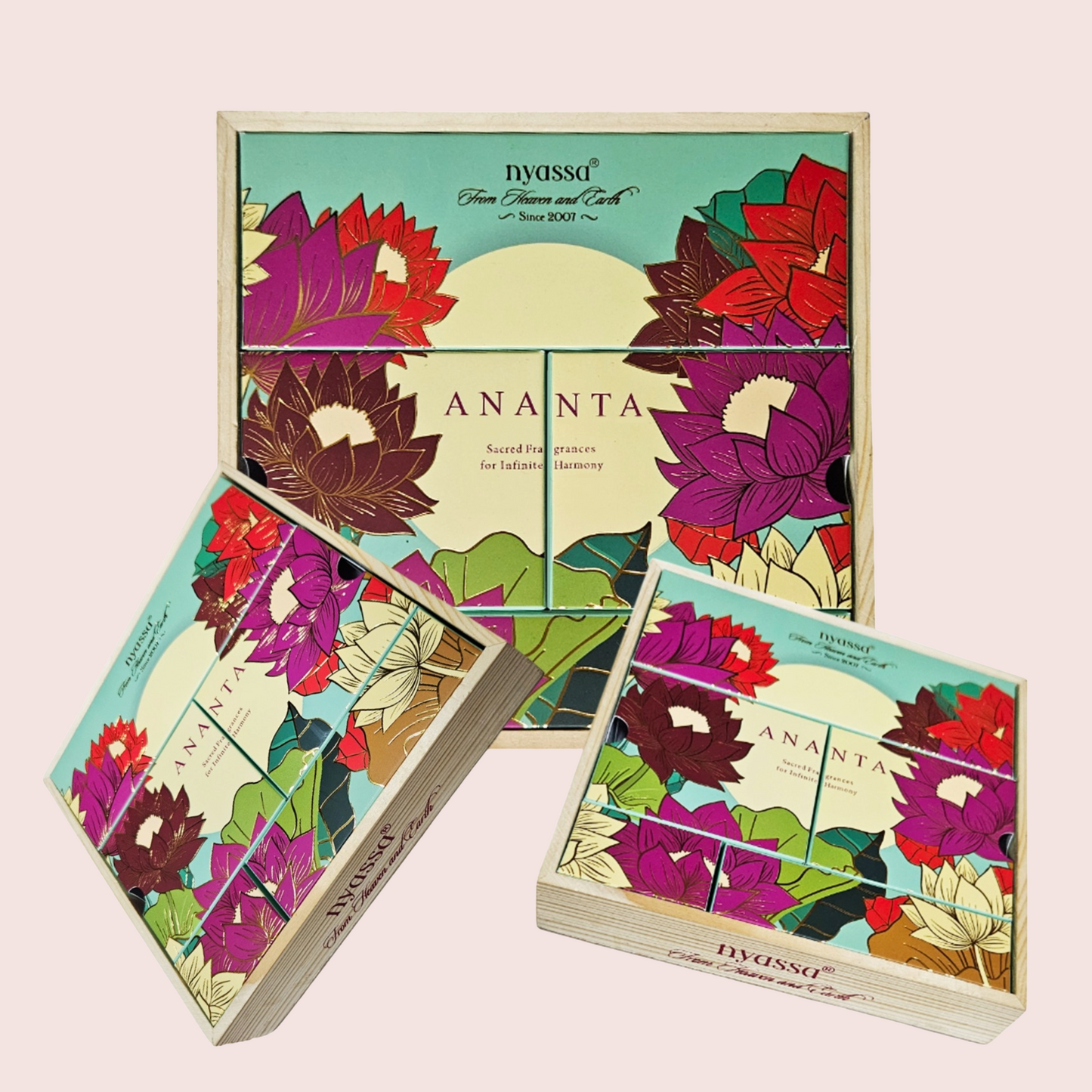Three boxes of IVASSO Ananta loose-leaf tea arranged on a pale pink background, with one large box standing behind two smaller boxes. The packaging features a colorful floral design with lotus and hibiscus flowers in purple, red, green, and cream.