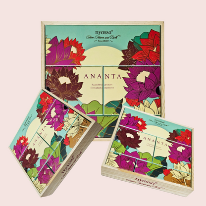 Three boxes of IVASSO Ananta loose-leaf tea arranged on a pale pink background, with one large box standing behind two smaller boxes. The packaging features a colorful floral design with lotus and hibiscus flowers in purple, red, green, and cream.