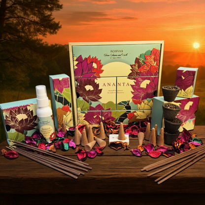 A Bhipani Ananta Sacred Space kit arranged on a wooden table against a sunset landscape background. The set includes a large floral-patterned box, smaller matching boxes, a white spray bottle, incense sticks, cone-shaped incense holders, and dried flower petals.