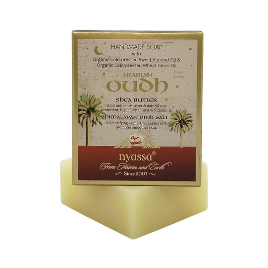 Nyassu Arabic Oudh Handmade Soap in a gold-colored cardboard box, displayed on a matching gold-colored geometric stand against a white background.