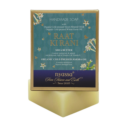 Nyassa Raat Kirani handmade soap in a gold rectangular box with a teal and purple label, displayed on a matching gold stand against a white background.