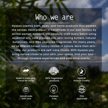 A promotional graphic with a dark semi-transparent text panel over a blurred outdoor background of green foliage and blue sky. The panel reads 'Who we are' and describes Nyassa's handmade bath, body, and home products, with six icons below highlighting 'Made in India and "Vocal for Local"', '100% Vegetarian products', 'Against Animal Cruelty', 'Handmade with love', 'Paraben Free', and 'FDA Approved'.