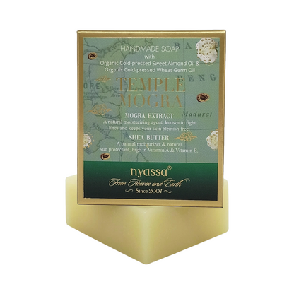Nyassa Temple Mogra handmade soap in a gold-framed rectangular box with a green and teal label, displayed on a matching gold geometric stand against a white background.