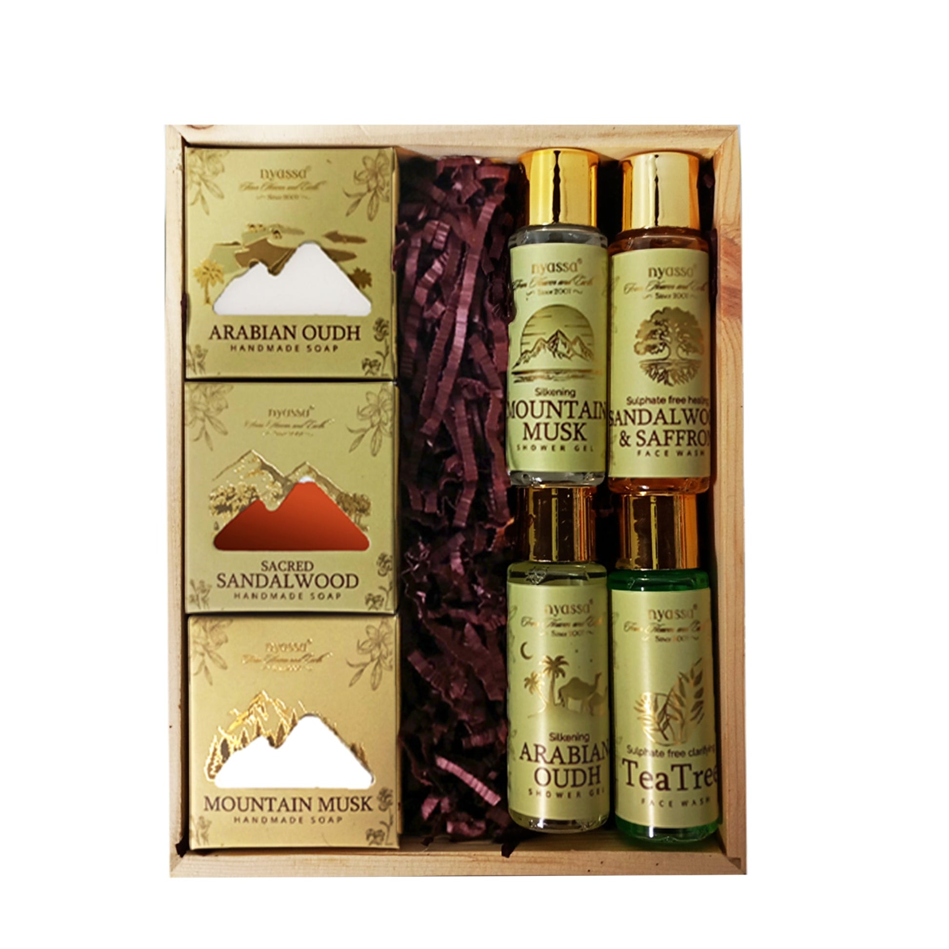 A boxed gift set containing four handcrafted Arabian Oudh sandalwood hand warmers, two Mountain Musk & Saffron body lotions, and two Sacred Sandalwood hand warmers, arranged in a wooden tray with purple shredded paper.