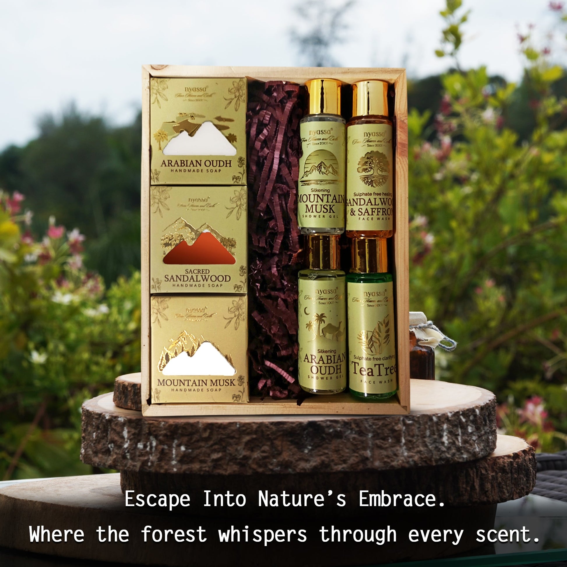 A boxed fragrance gift set displayed outdoors on a rustic wood slice stand. The set includes a tall rectangular box and four cylindrical bottles with gold caps, all in matching beige packaging with green labels.